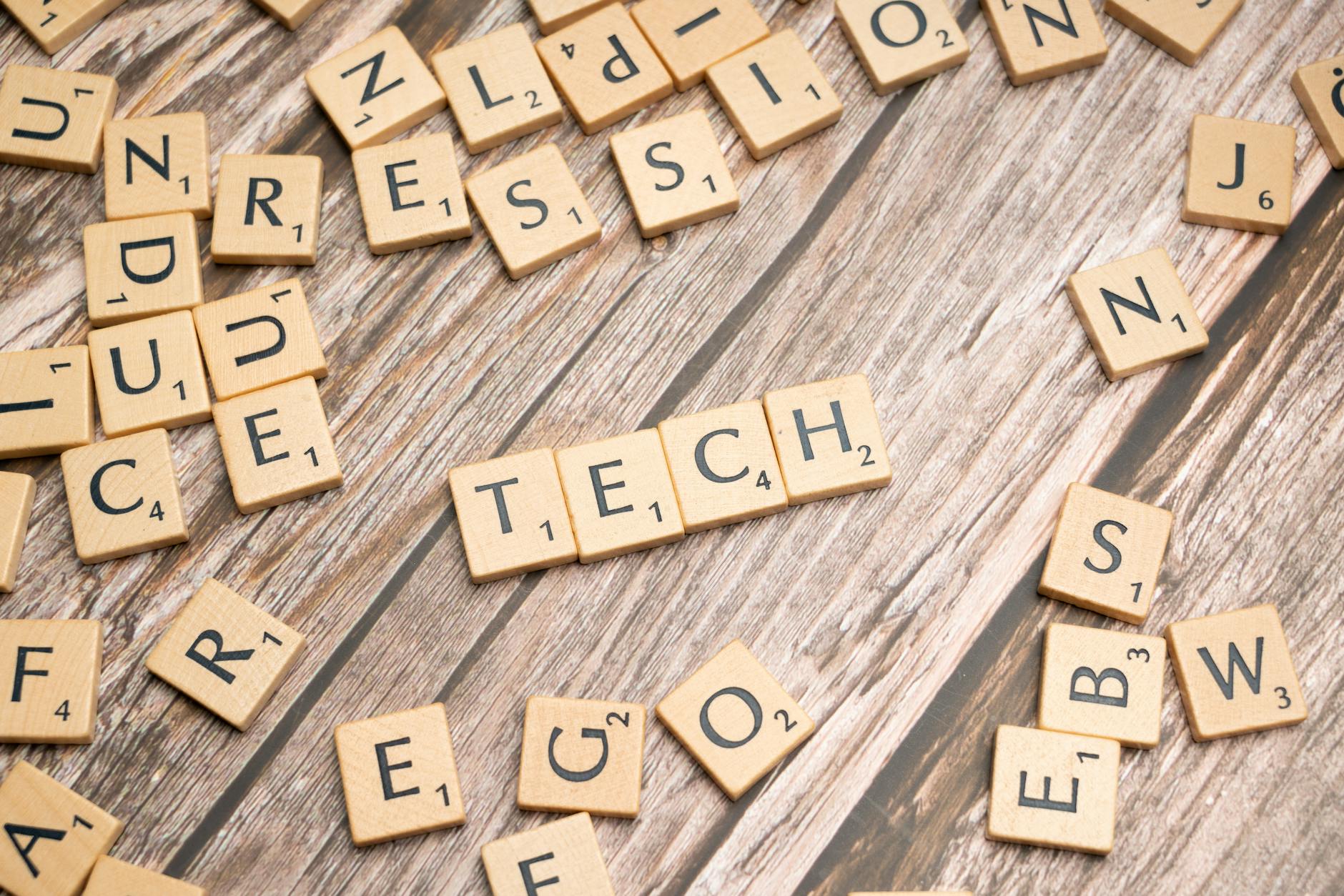 scrabble letters spelling out tech on a wooden table